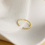 unusual womens wedding bands​, 5A CZ band ring, modern promise ring, cubic zirconia Rings, cz ring, wedding rings cz, eamti rings, cheap wedding rings under $50, copper ring, open band rings, open wedding band​. Gold ring with small diamonds on a light beige fabric background