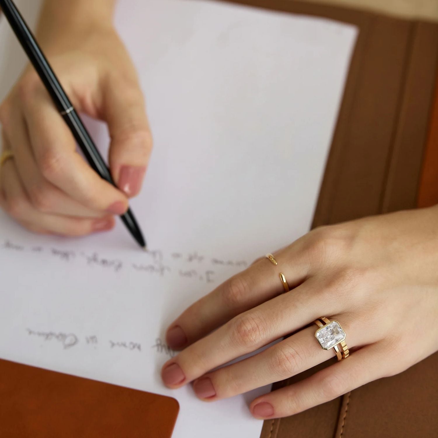 minimalist wedding band ring, 5A CZ band ring, modern promise ring, cubic zirconia Rings, cz ring, wedding rings cz, eamti rings, cheap wedding rings under $50, copper ring, Person writing on a piece of paper with a pen, wearing a gold ring with a diamond.