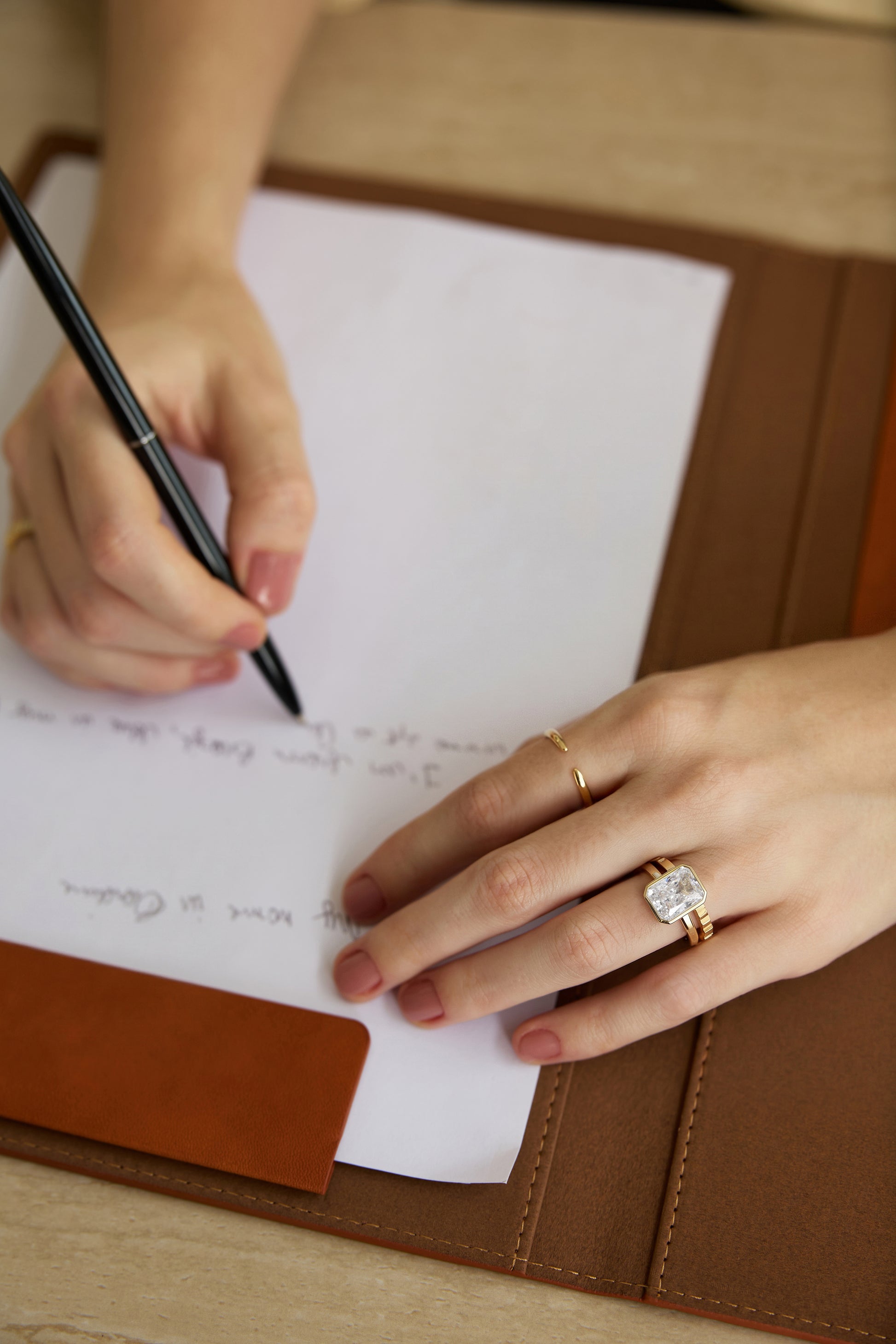 minimalist wedding band ring, 5A CZ band ring, modern promise ring, cubic zirconia Rings, cz ring, wedding rings cz, eamti rings, cheap wedding rings under $50, copper ring, Person writing on a piece of paper with a pen, wearing a gold ring with a diamond.